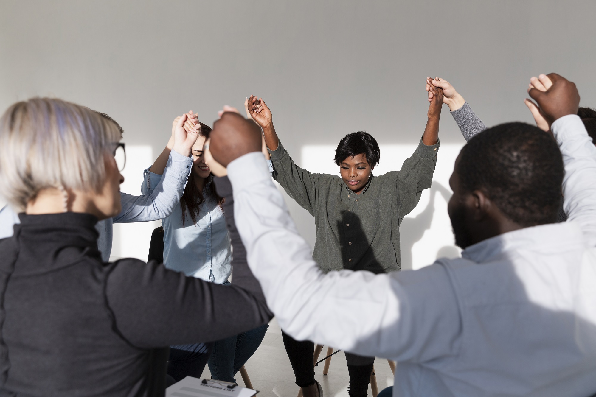 A community holding hands and raising their arms together in prayer